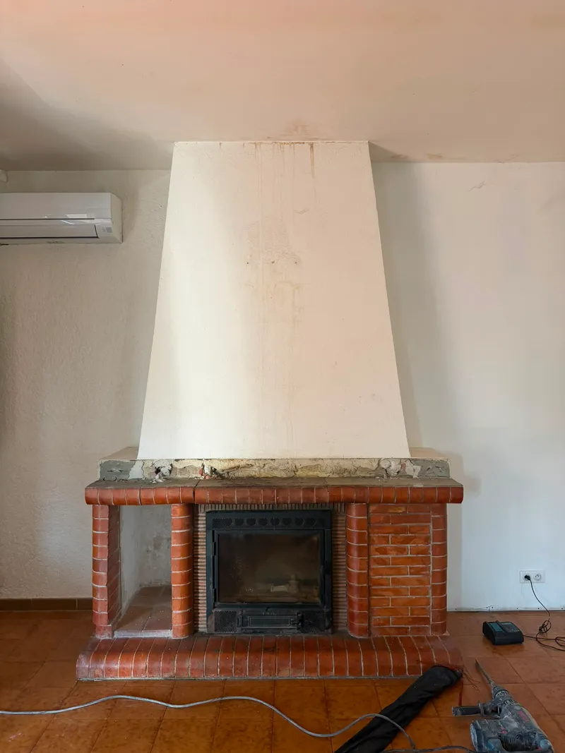 Cheminée à insert avec socle en briques et grande hotte maçonnée blanche, avant démolition